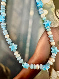 A beaded necklace with light blue starfish charms and pale blue oval beads, mixed with white freshwater pearl beads.