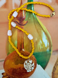 Yellow beaded necklace with a shell pendant.