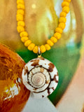 Necklace with yellow beads and a shell pendant.