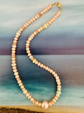 A strand of irregular peach freshwater pearls with a gold clasp.