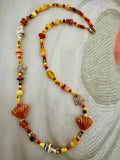A handmade beaded necklace featuring yellow, red, and orange beads, shell charms, starfish charms, and a gold clasp.