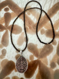 A smoky quartz gemstone necklace with an oval silver-toned antique victorian pendant locket.