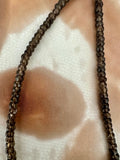 A close-up of a beaded necklace made of small faceted dark brown to smoky translucent beads.